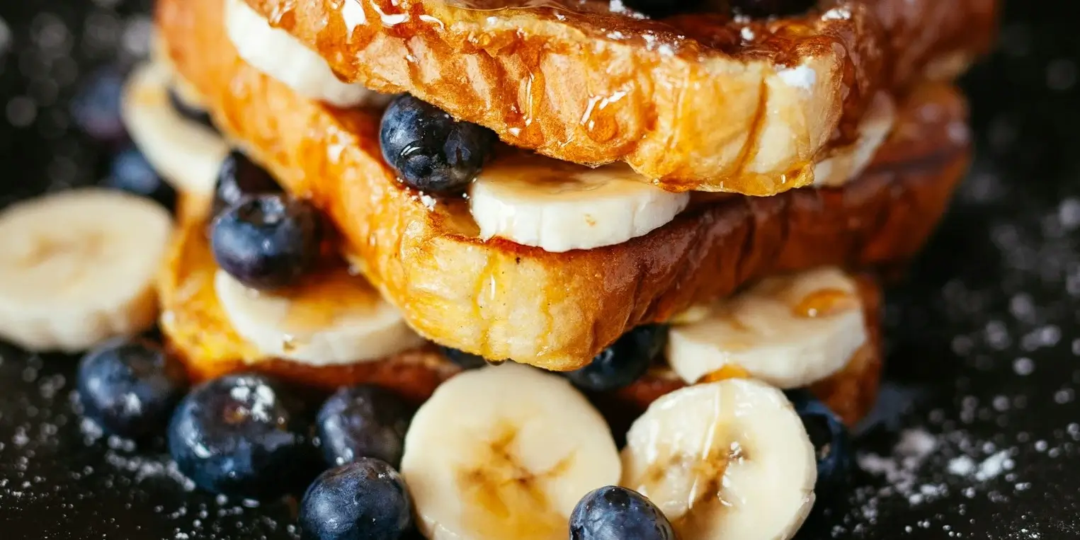 Photo of french toast with syrup, blueberries, banana